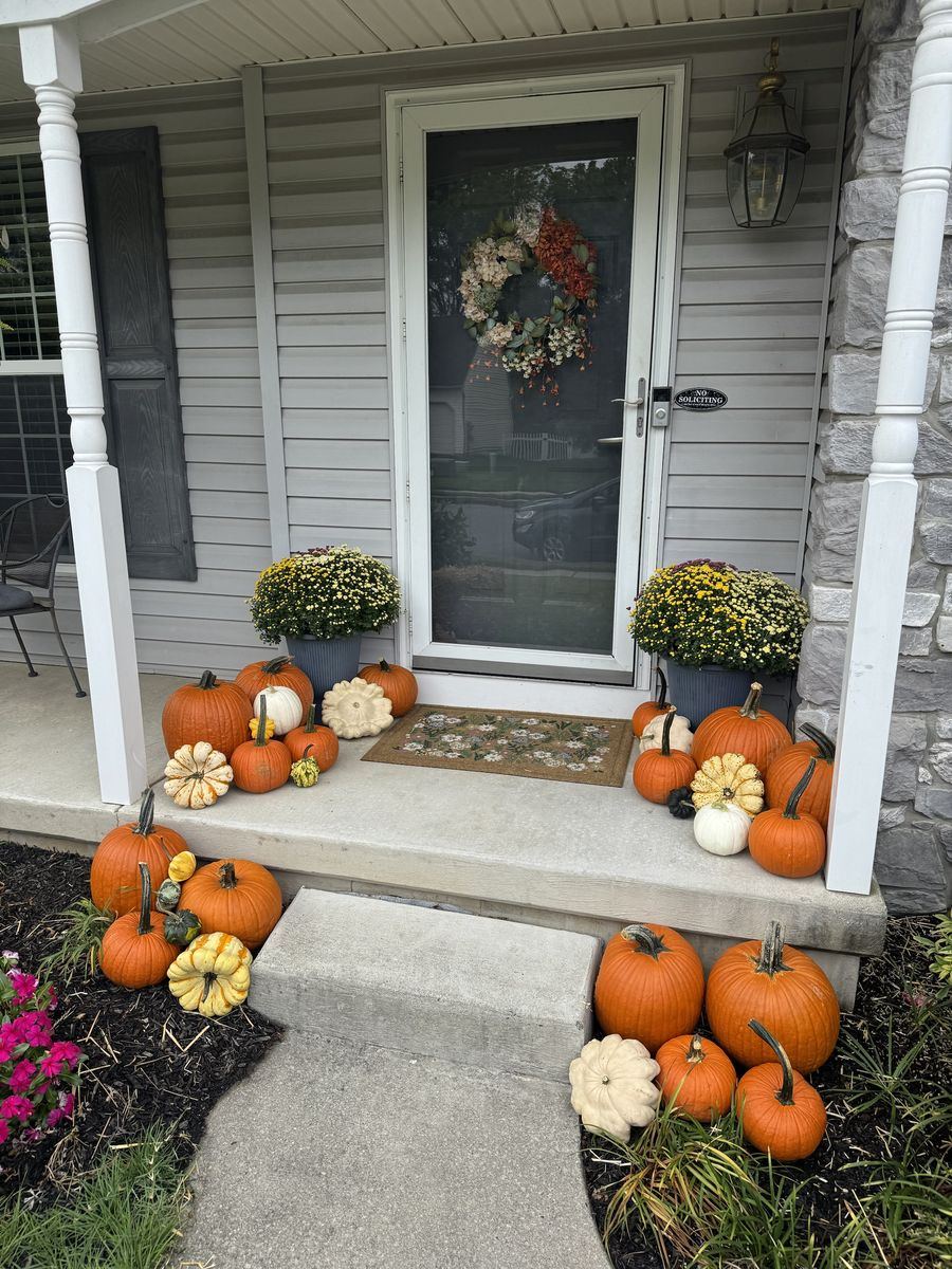 The same porch styled with orange, white and striped pumpkins, gourds and two mums